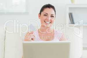 Smiling woman using a laptop and holding a credit card
