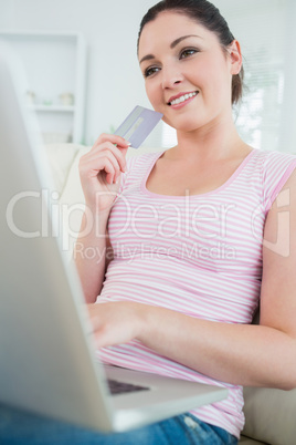 Woman sitting on a couch with a laptop and a credit card