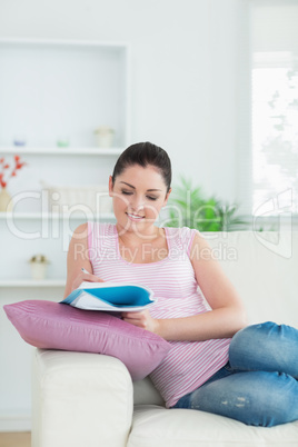 Woman taking notes while relaxing on the couch