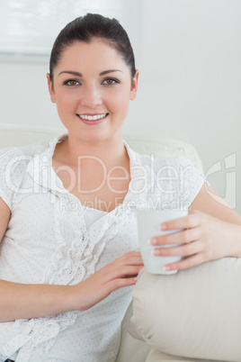 Woman holding a cup sitting on a couch and relaxing