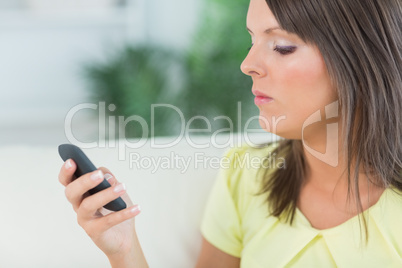 Serious woman using her smartphone at home