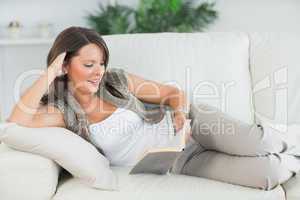 Woman lying on sofa and reading her book