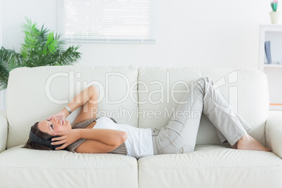 smiling woman lying on the sofa and listening music