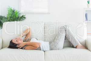 smiling woman lying on the sofa and listening music