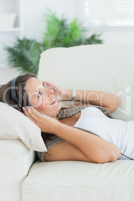 Happy woman lying on the sofa and listening music