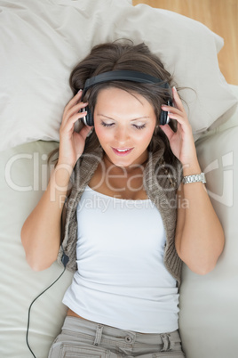 Calm woman lying on the sofa and listening music