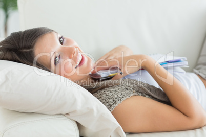 Woman clutching notepad lying on the sofa