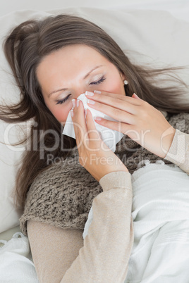 Woman lying on sofa and blowing nose