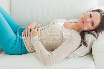 Anxious and sick woman lying on sofa
