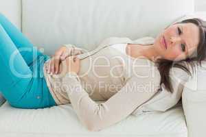 Anxious and sick woman lying on sofa