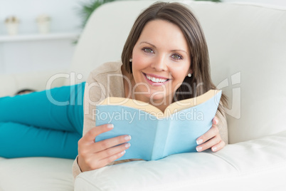 Happy women reading a book and lying on the sofa