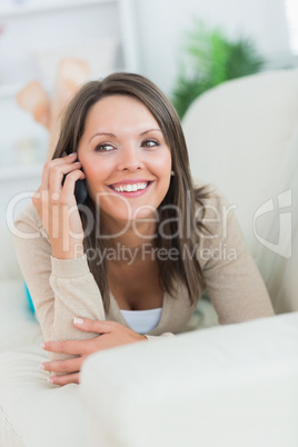 Happy woman lying on the sofa and calling