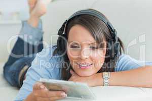 Happy woman listening music looking at cd on sofa