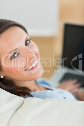 Happy woman using laptop on sofa