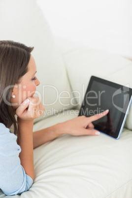 Woman lying on sofa using tablet pc