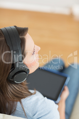 Woman listening music with her digital tablet on sofa