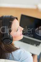 Woman listening music with her laptop on sofa