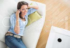 Brunette woman lying on sofa and calling