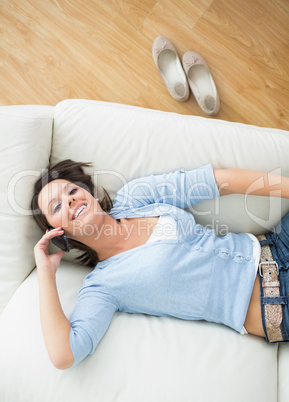 Smiling woman calling and lying back on sofa