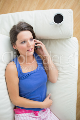 Woman in pyjamas calling on the sofa