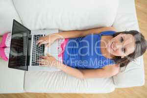 Smiling woman typing on her laptop wearing pyjamas