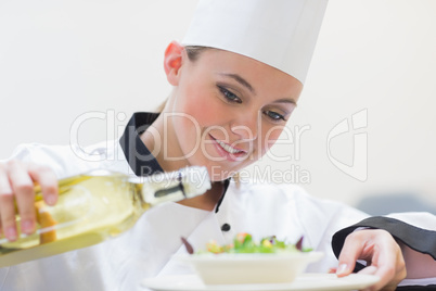 Chef pouring oil over salad