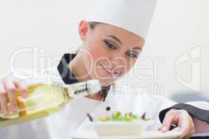 Chef pouring oil over salad