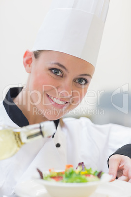 Smiling chef dressing a salad