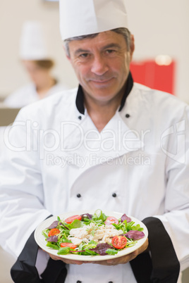 Cheerful chef presenting his salad