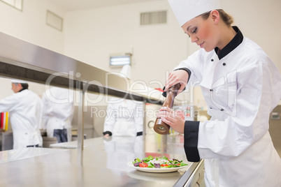 Chef seasoning salad with pepper