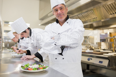 Chef smiling with others preparing salads