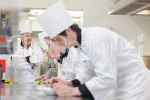 Chef overlooking others preparing salads