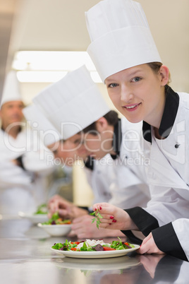 Smiling chef looking up from preparing salad