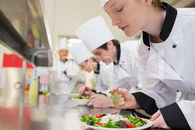 Chef finishing her salad in culinary class