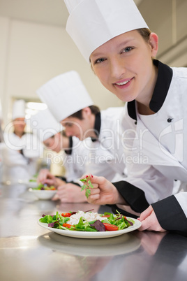 Smiling chef preparing salad in culinary class