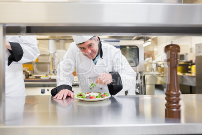 Smiling chef garnishing salad