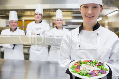 Smiling chef holding out a salad