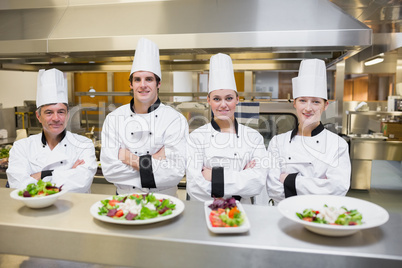 Smiling Chef's standing behind salads