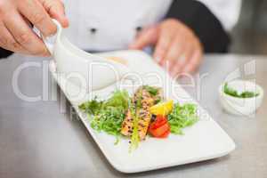 Chef pouring sauce on salmon dish