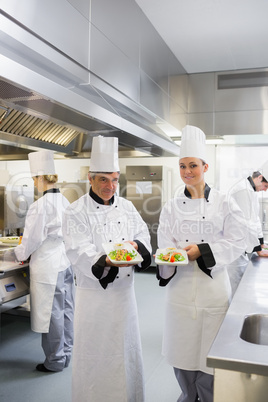 Two smiling Chef's showing salmon dishes