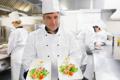 Chef holding out two salmon dishes