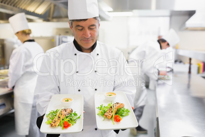 Chef admiring two salmon dishes in his hands