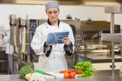Serious chef using digital tablet beside the vegetables