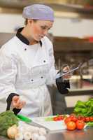 Chef consulting digital tablet before preparing vegetables