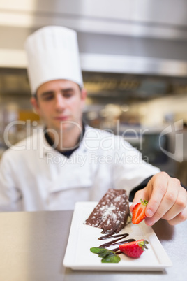 Chef putting a strawberry with the cake