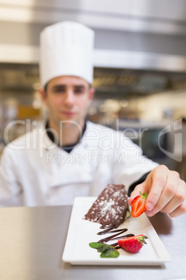 Chef putting a strawberry on dessert plate