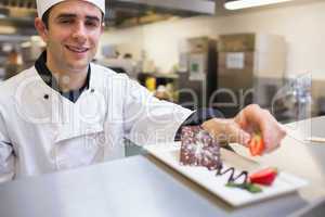 Smiling chef garnishing a slice of cake