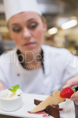 Chef putting strawberry on dessert plat