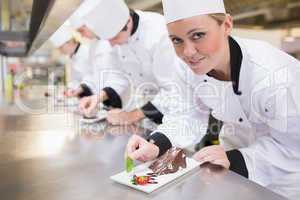 Smiling chef looking up from finishing dessert