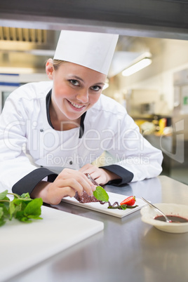 Smiling chef putting mint on the plate